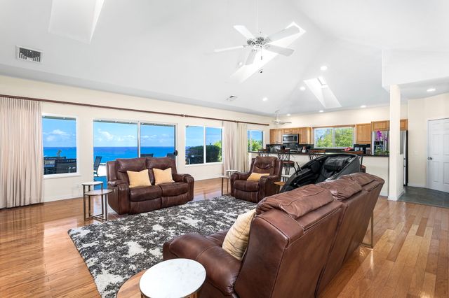 a living room with furniture kitchen view and a large window