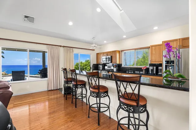 a kitchen with stainless steel appliances granite countertop a stove top oven a sink a dining table and chairs with wooden floor