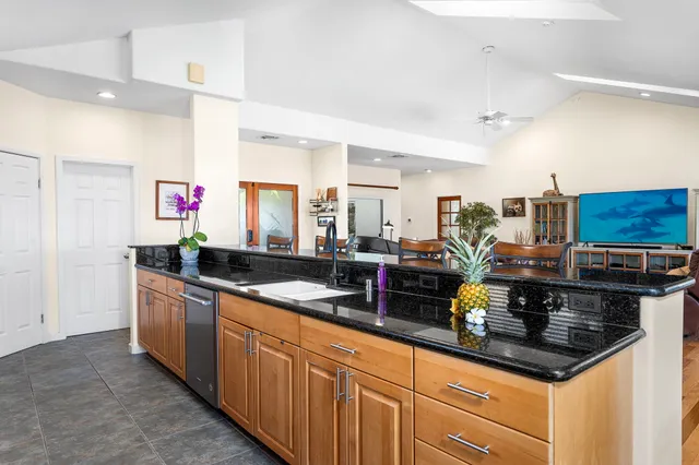 a kitchen with granite countertop a sink a counter top space cabinets and stainless steel appliances
