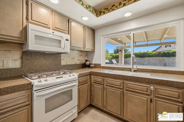 a kitchen with cabinets appliances a sink and a window