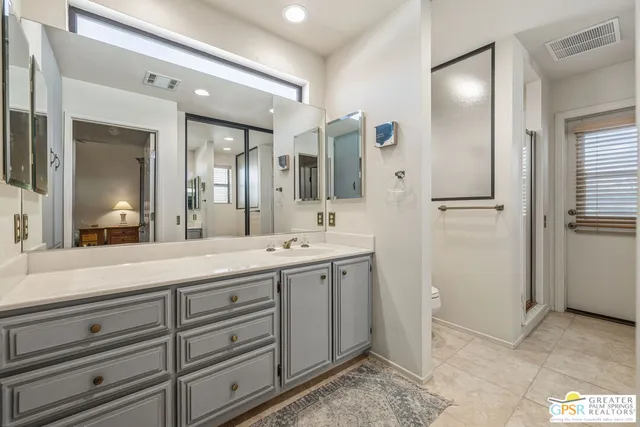 a spacious bathroom with a double vanity sink a mirror and a shower