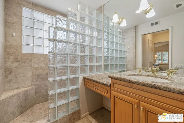 a bathroom with a granite countertop sink a mirror and a shower