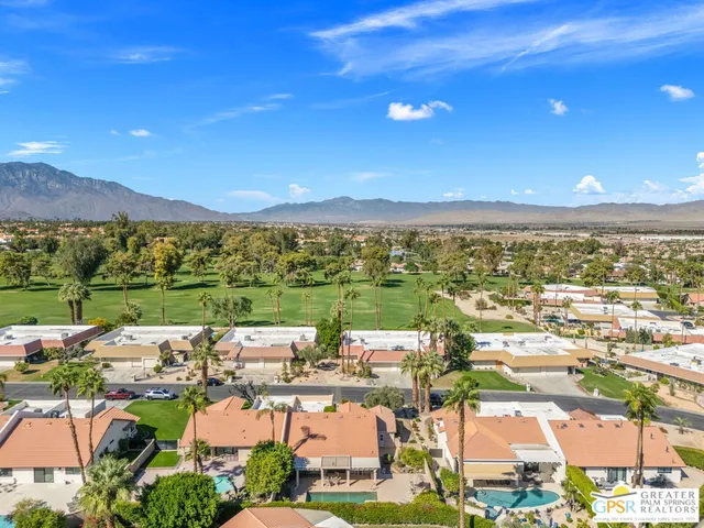 an aerial view of a city with lots of residential buildings ocean and mountain view in back
