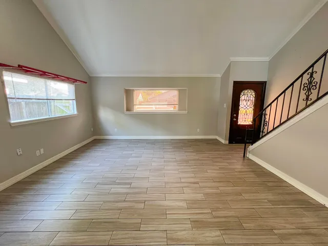 a view of an empty room with wooden floor and a window