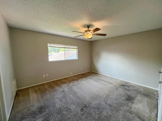 an empty room with windows and ceiling fan