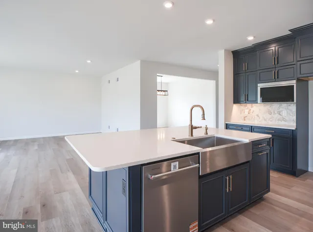 a living room with stainless steel appliances kitchen island granite countertop a large counter top and wooden floors
