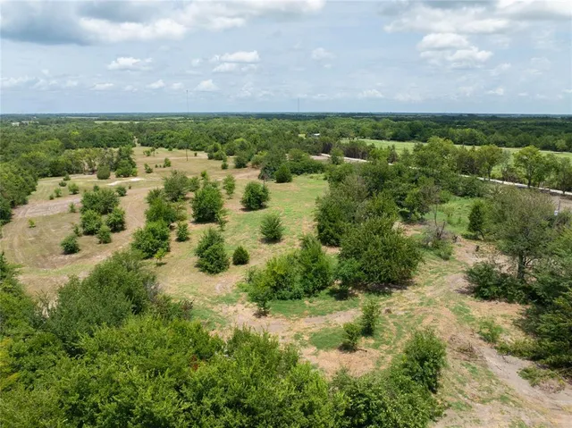 an aerial view of residential houses with outdoor space and trees