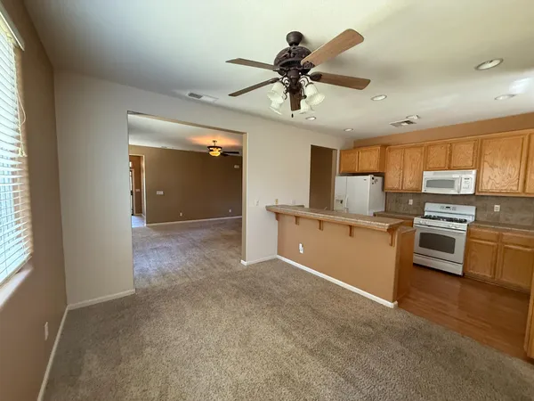 an empty room with chandelier fan and windows