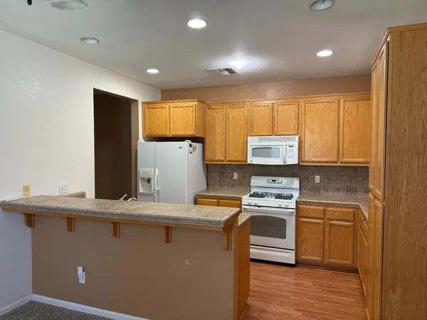 a kitchen with granite countertop cabinets stainless steel appliances a sink and wooden floor