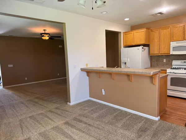 a view of a kitchen with furniture a ceiling fan and windows
