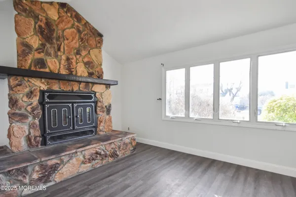 a view of a livingroom with wooden floor a fireplace and windows