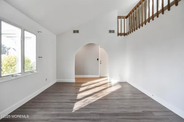 a view of an empty room with wooden floor and window