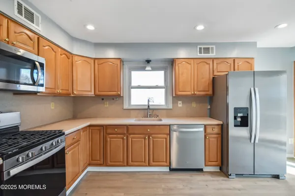 a kitchen with stainless steel appliances granite countertop a stove a sink dishwasher a refrigerator and a microwave