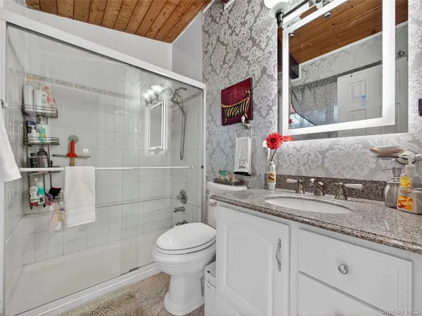 a bathroom with a granite countertop sink mirror vanity and toilet