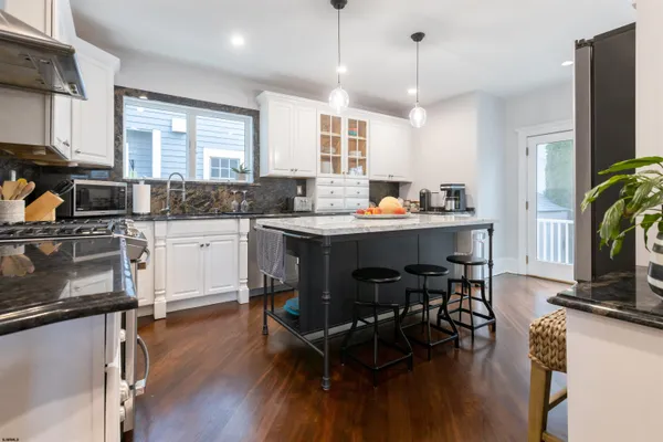 a kitchen with stainless steel appliances granite countertop a table chairs refrigerator and sink