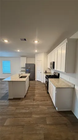 a large room with kitchen island a sink a center island stainless steel appliances and a window