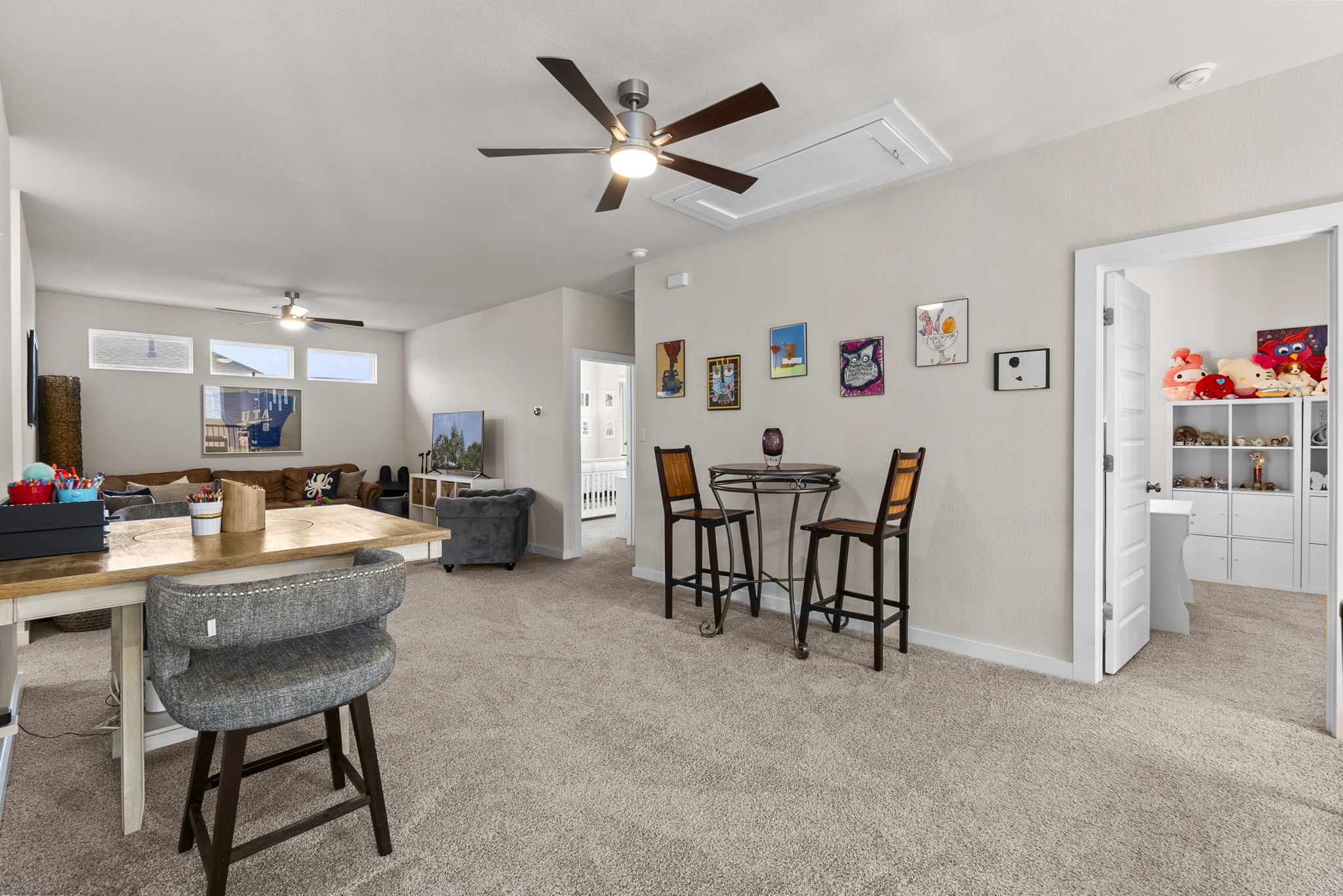 460 Constitution Way Kyle, TX 78640 - Photo 25 of 40 Expansive open-concept room featuring neutral-toned carpeting, two ceiling fans with integrated lighting, and multiple windows providing natural illumination