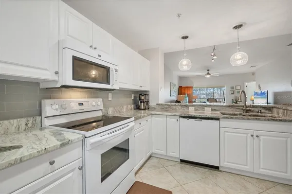 a kitchen with granite countertop white cabinets and white appliances