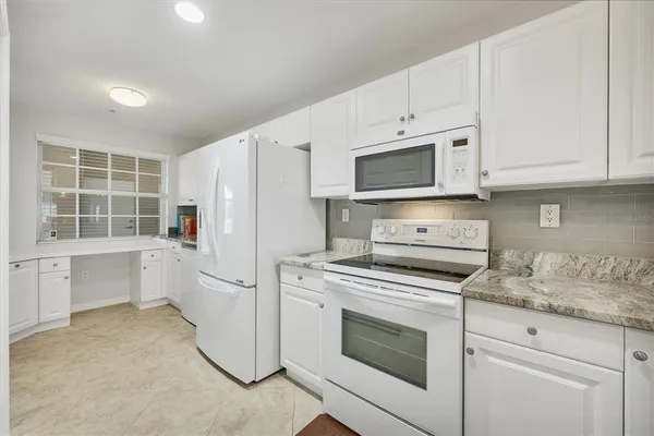 a kitchen with white cabinets and white appliances
