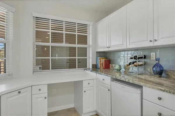 a kitchen with granite countertop white cabinets and a window