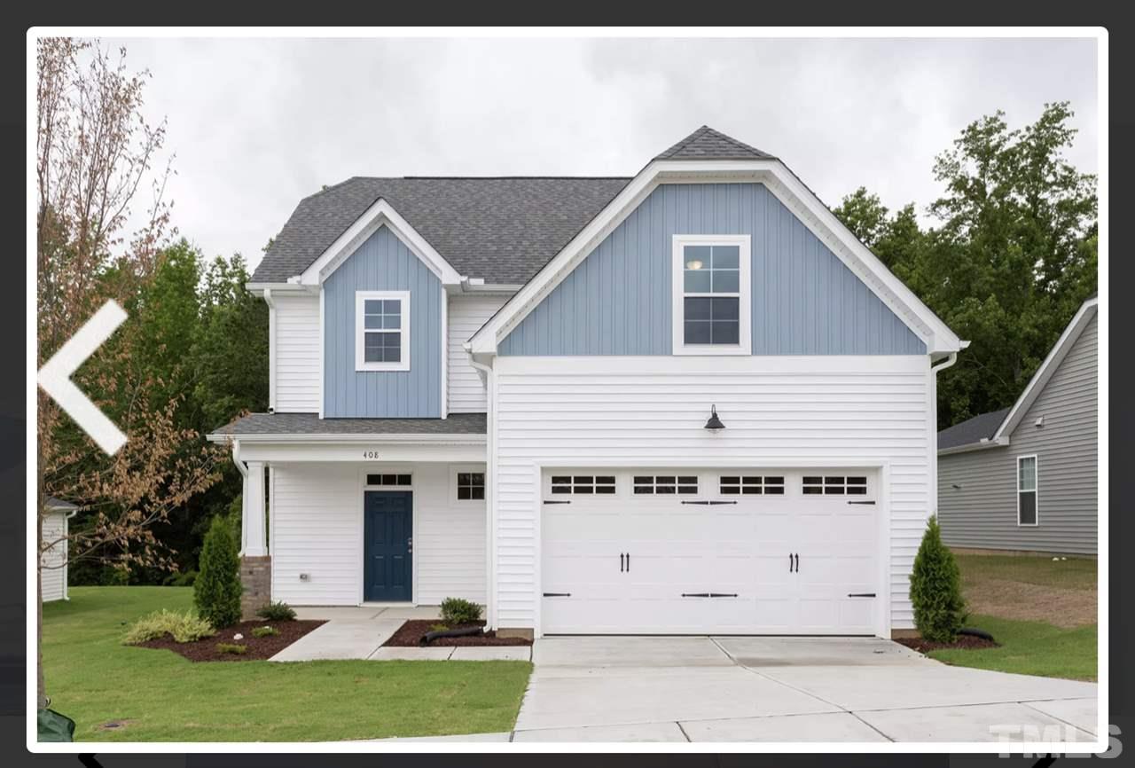 a view of a white house with a yard and table and chairs under an umbrella