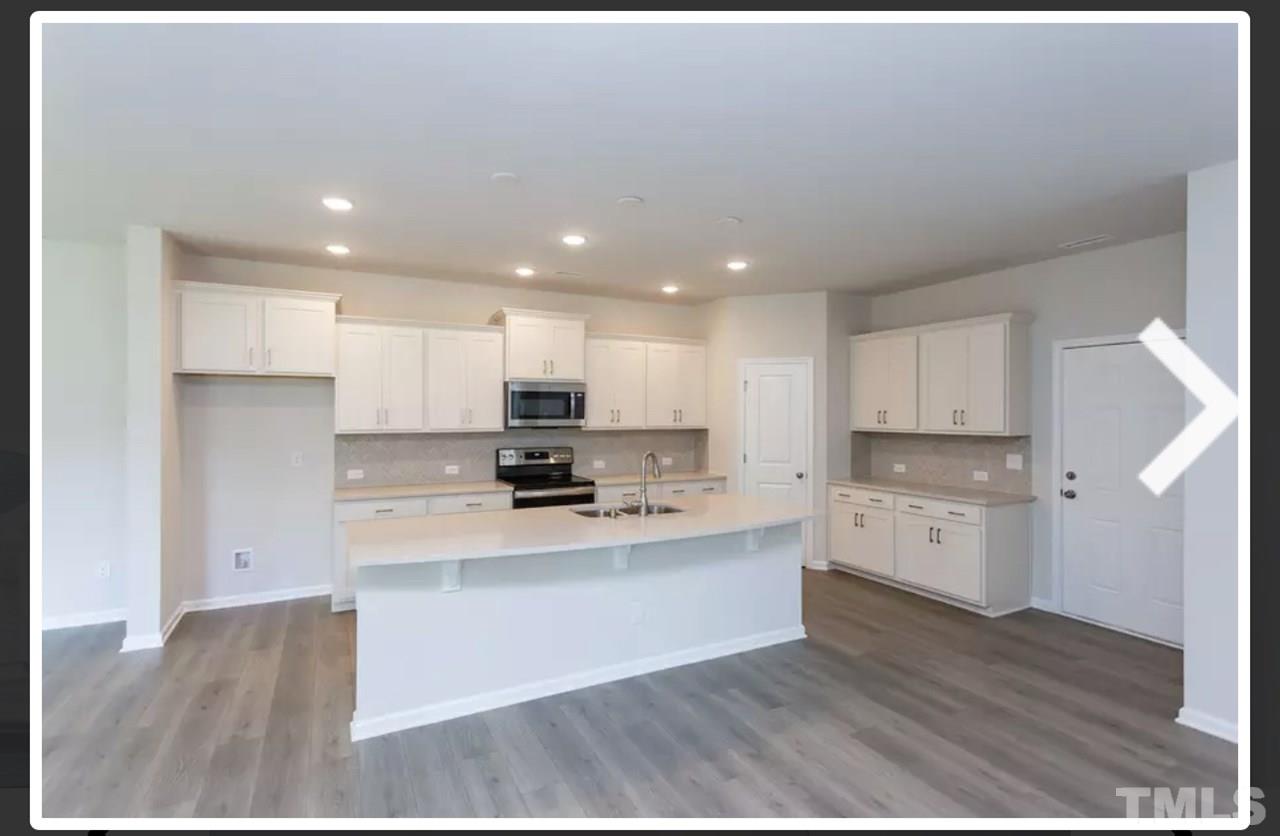 234 Hopper Circle Clayton, NC 27520 - Photo 7 of 22 a large kitchen with stainless steel appliances kitchen island granite countertop a stove a sink and white cabinets