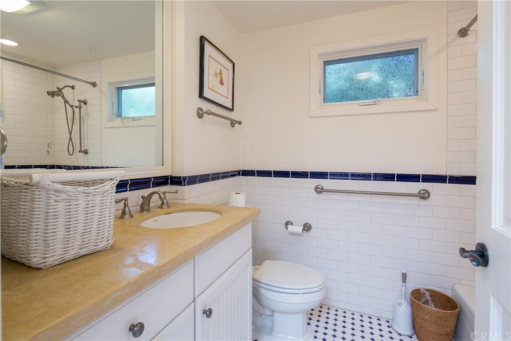 652 Agate Street Laguna Beach, CA 92651 - Photo 18 of 19 a bathroom with a granite countertop sink a toilet and mirror