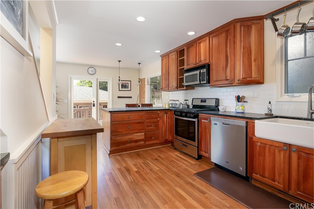 652 Agate Street Laguna Beach, CA 92651 - Photo 10 of 19 a kitchen with stainless steel appliances granite countertop wooden cabinets a stove a sink and a microwave