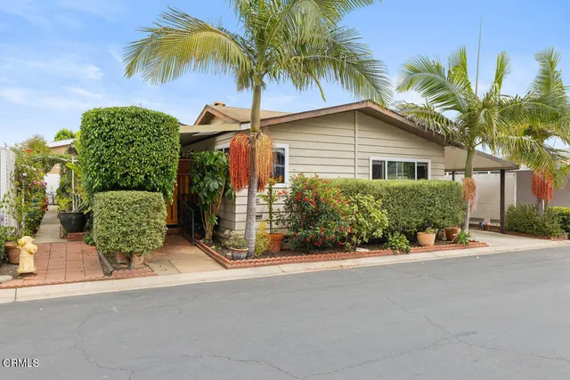 front view of a house with a yard and palm trees
