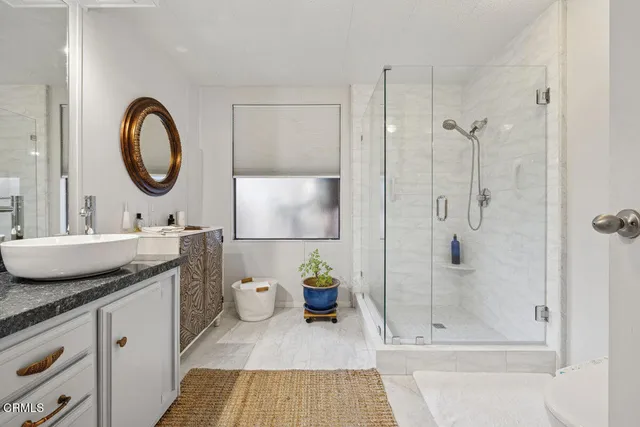 a spacious en suite bathroom with a granite countertop double vanity sink and a mirror