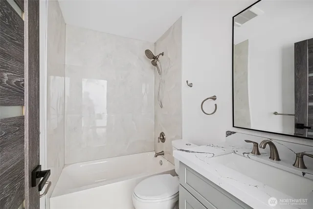 a bathroom with a toilet a sink a mirror a bathtub and shower