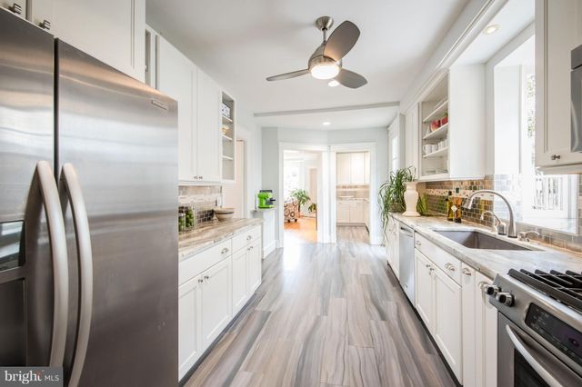 a large kitchen with a lot of counter space a sink and stainless steel appliances