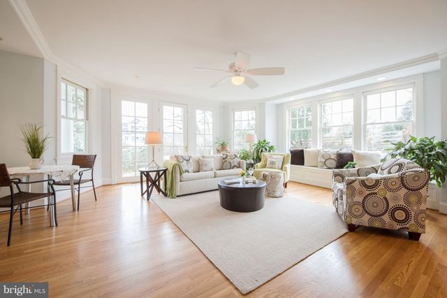 a living room with furniture a large window and wooden floor