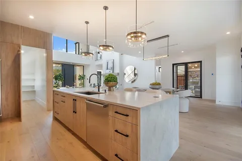a kitchen with kitchen island granite countertop a sink a center island a refrigerator and a wooden floor