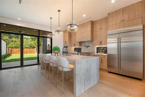 a kitchen with kitchen island a large counter top space appliances and a chandelier