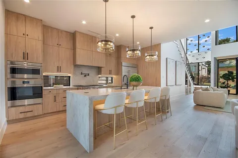 a large kitchen with kitchen island granite countertop a stove a sink a center island a dining table and chairs