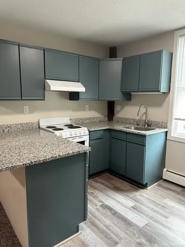 a kitchen with granite countertop a sink a stove and cabinets
