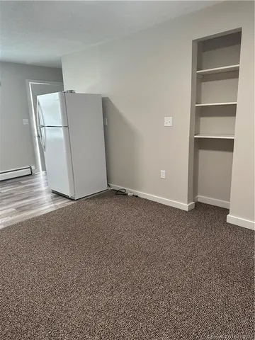 a view of a room with a refrigerator and cabinet