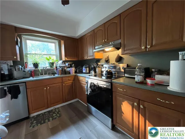 a kitchen with granite countertop wooden cabinets stainless steel appliances a sink and a window