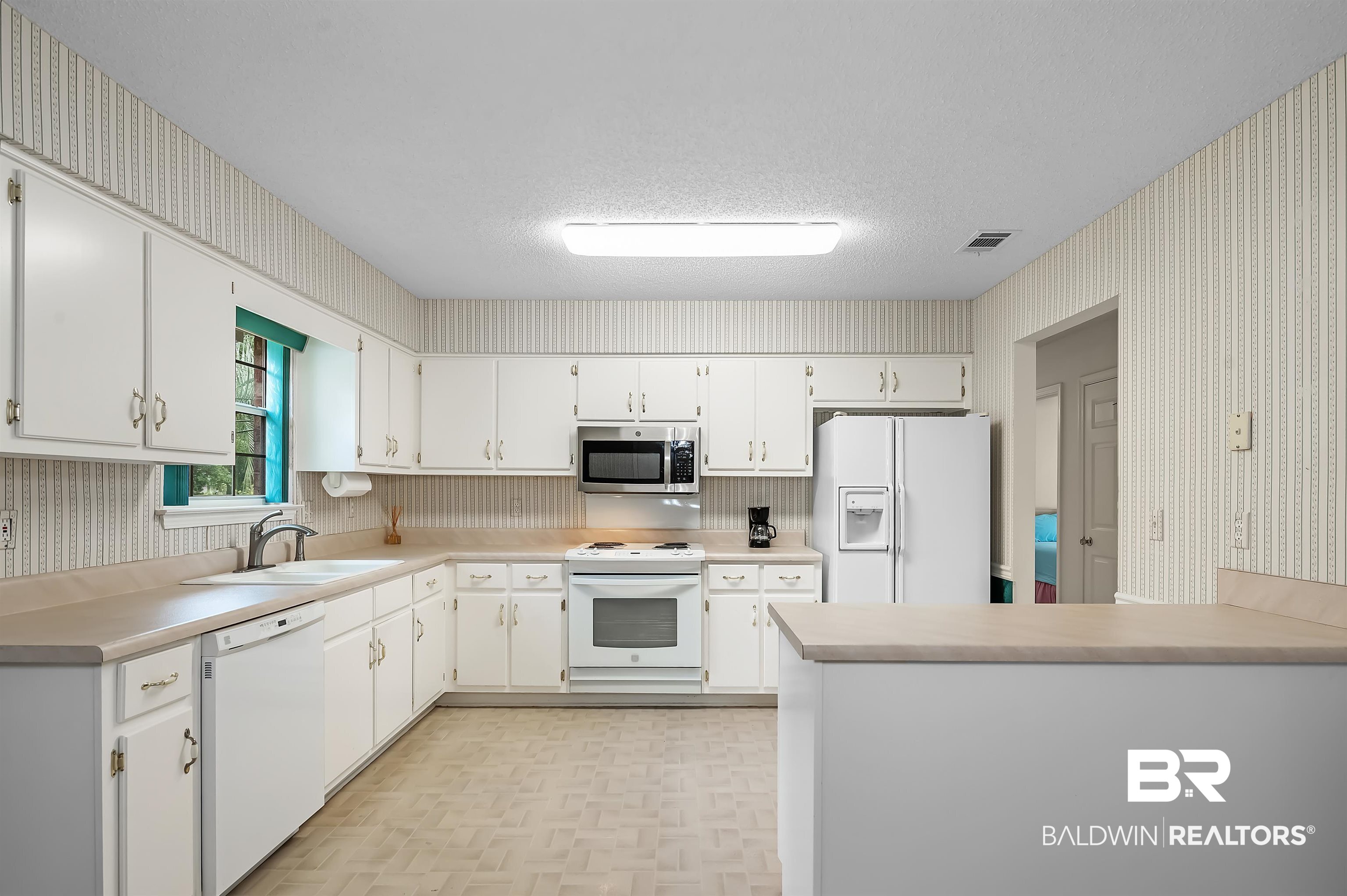 1502 Mulberry Lane Foley, AL 36535 - Photo 13 of 45 Kitchen with white appliances, kitchen peninsula, light parquet floors, white cabinets, and sink