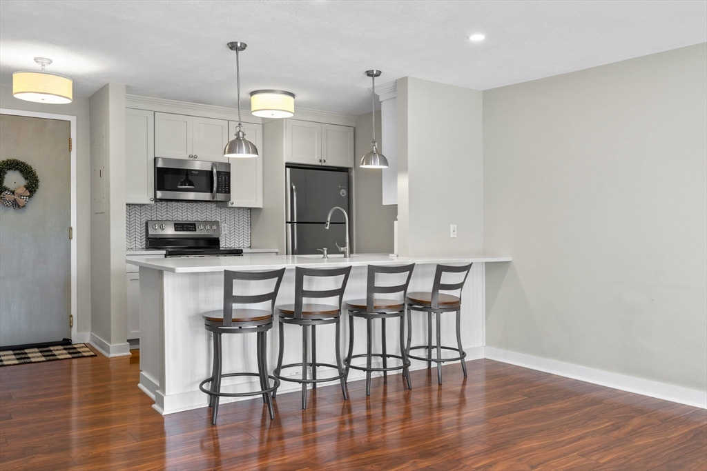 269 Cambridge Road, Unit 203 Woburn, MA 01801 - Photo 4 of 26 a kitchen with stainless steel appliances a dining table chairs and granite counter tops