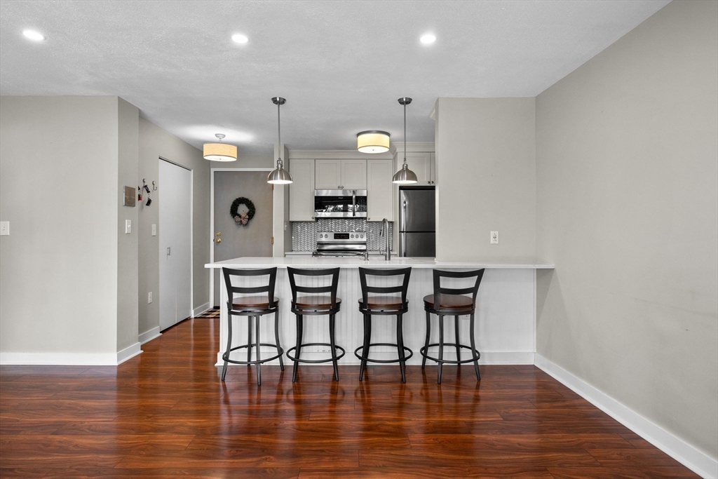 269 Cambridge Road, Unit 203 Woburn, MA 01801 - Photo 6 of 26 a kitchen with stainless steel appliances a dining table chairs and chandelier