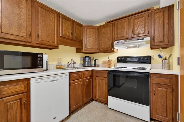 a kitchen with granite countertop wooden cabinets and white appliances