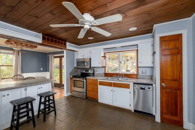 a kitchen with stainless steel appliances kitchen island granite countertop a sink cabinets and wooden floor
