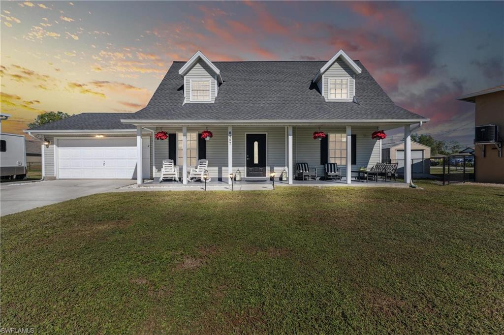 8457 Wren Road Fort Myers, FL 33967 - Photo 2 of 50 View of front of home with central air condition unit, a yard, covered porch, and a garage