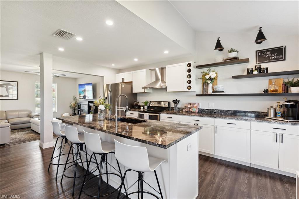 8457 Wren Road Fort Myers, FL 33967 - Photo 22 of 50 Kitchen featuring stainless steel appliances, a kitchen island with sink, and wall chimney exhaust hood