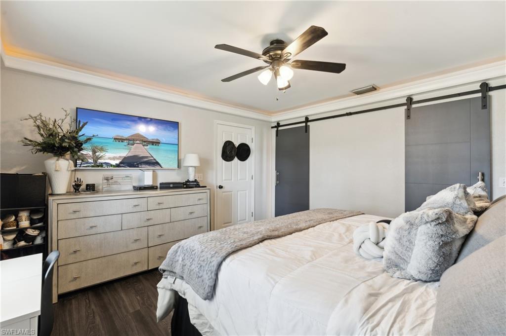 8457 Wren Road Fort Myers, FL 33967 - Photo 25 of 50 Bedroom with a barn door, dark hardwood / wood-style floors, and ceiling fan