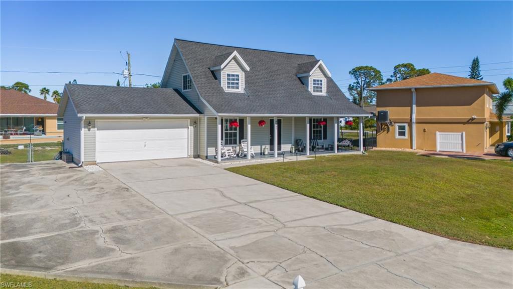 8457 Wren Road Fort Myers, FL 33967 - Photo 4 of 50 New england style home with covered porch, a garage, and a front yard