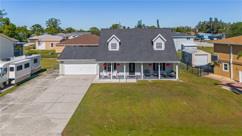 8457 Wren Road Fort Myers, FL 33967 - Photo 5 of 50 View of front of property with central AC unit, a garage, covered porch, and a front lawn