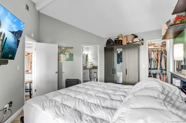 a bedroom with a bed and dresser with wooden floor
